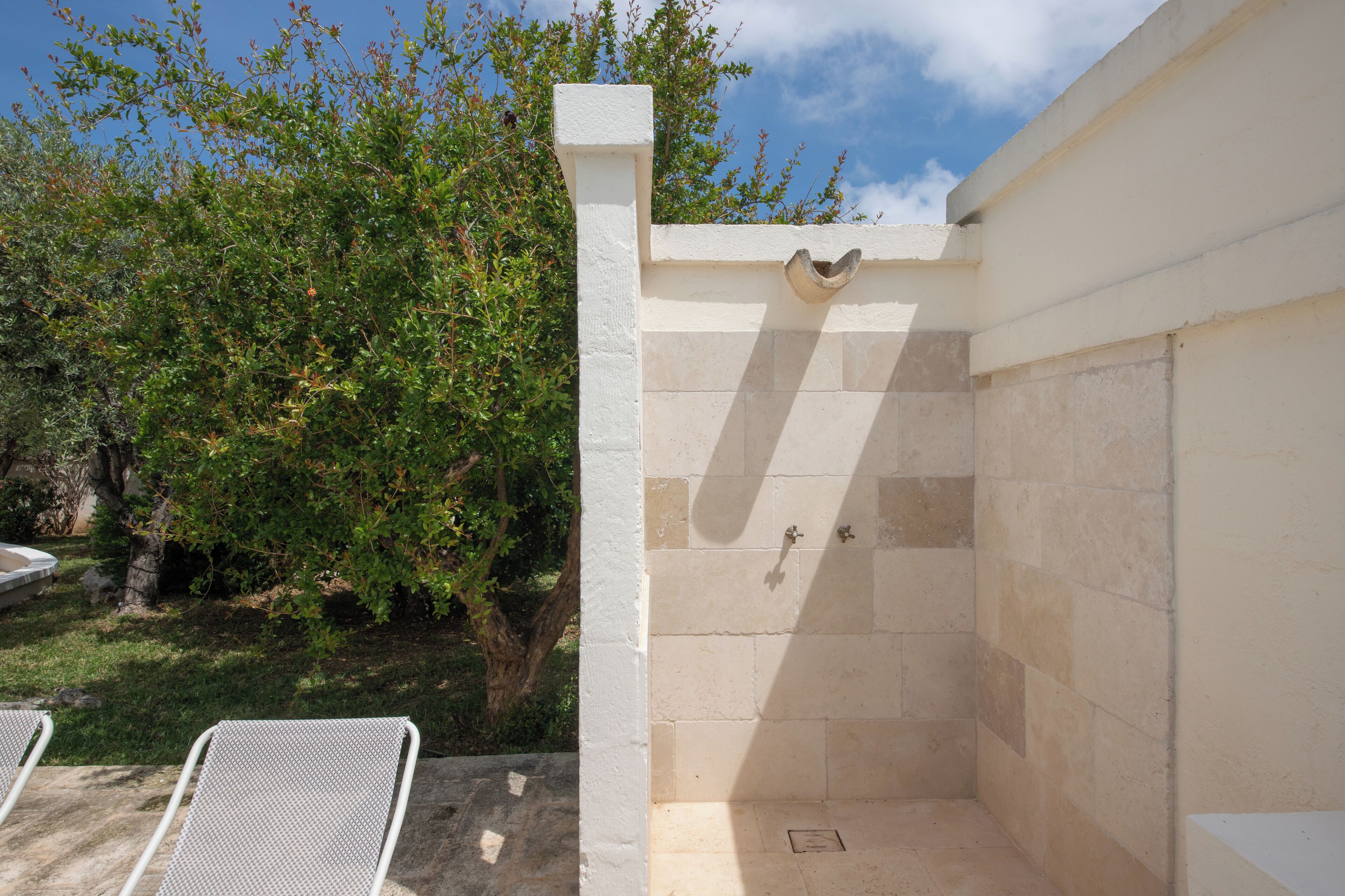 Un espacio de ducha pequeño y cerrado, con paredes de azulejos y un pilar blanco.
