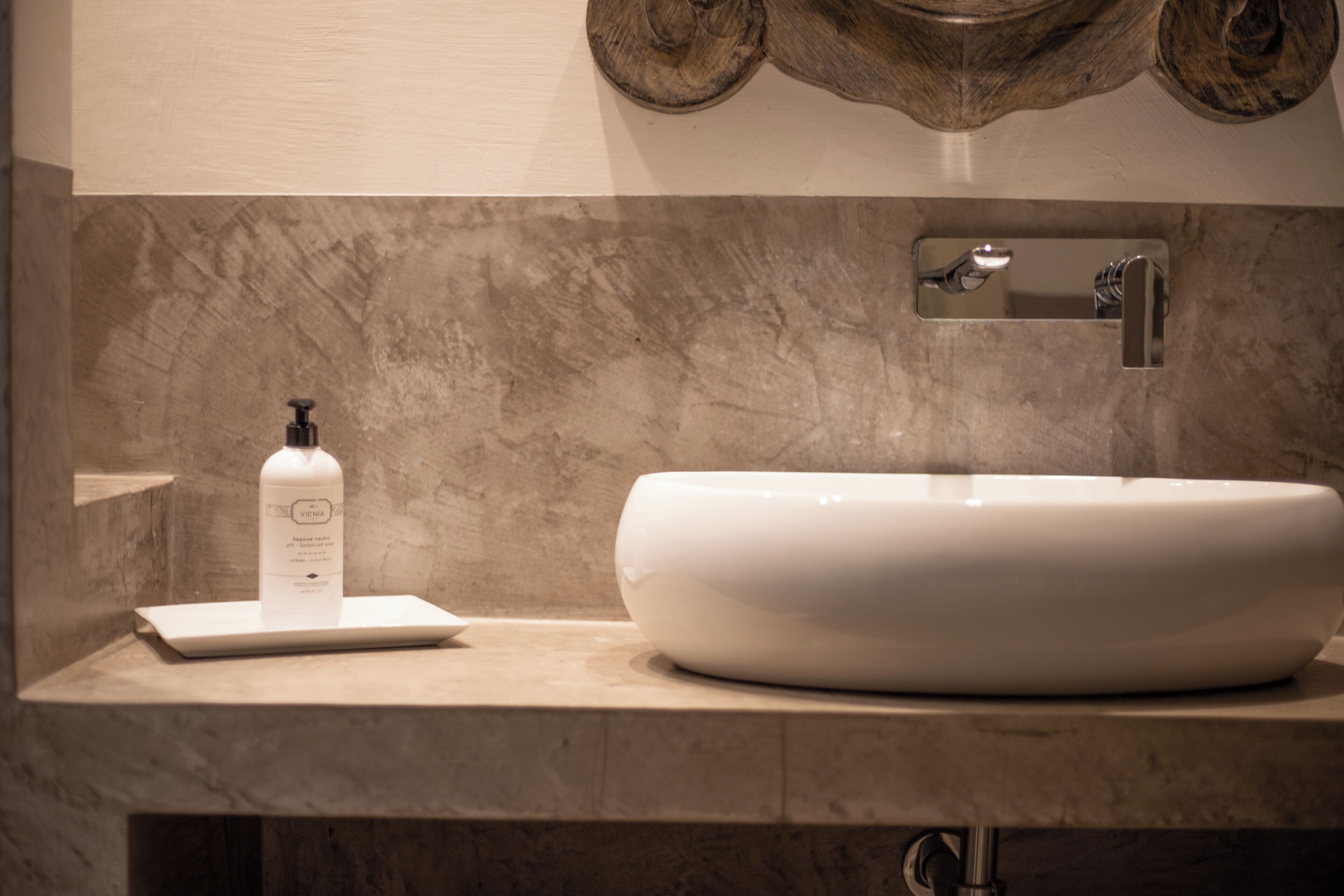 Un baño con un lavabo blanco, una botella de jabón para manos y un espejo.