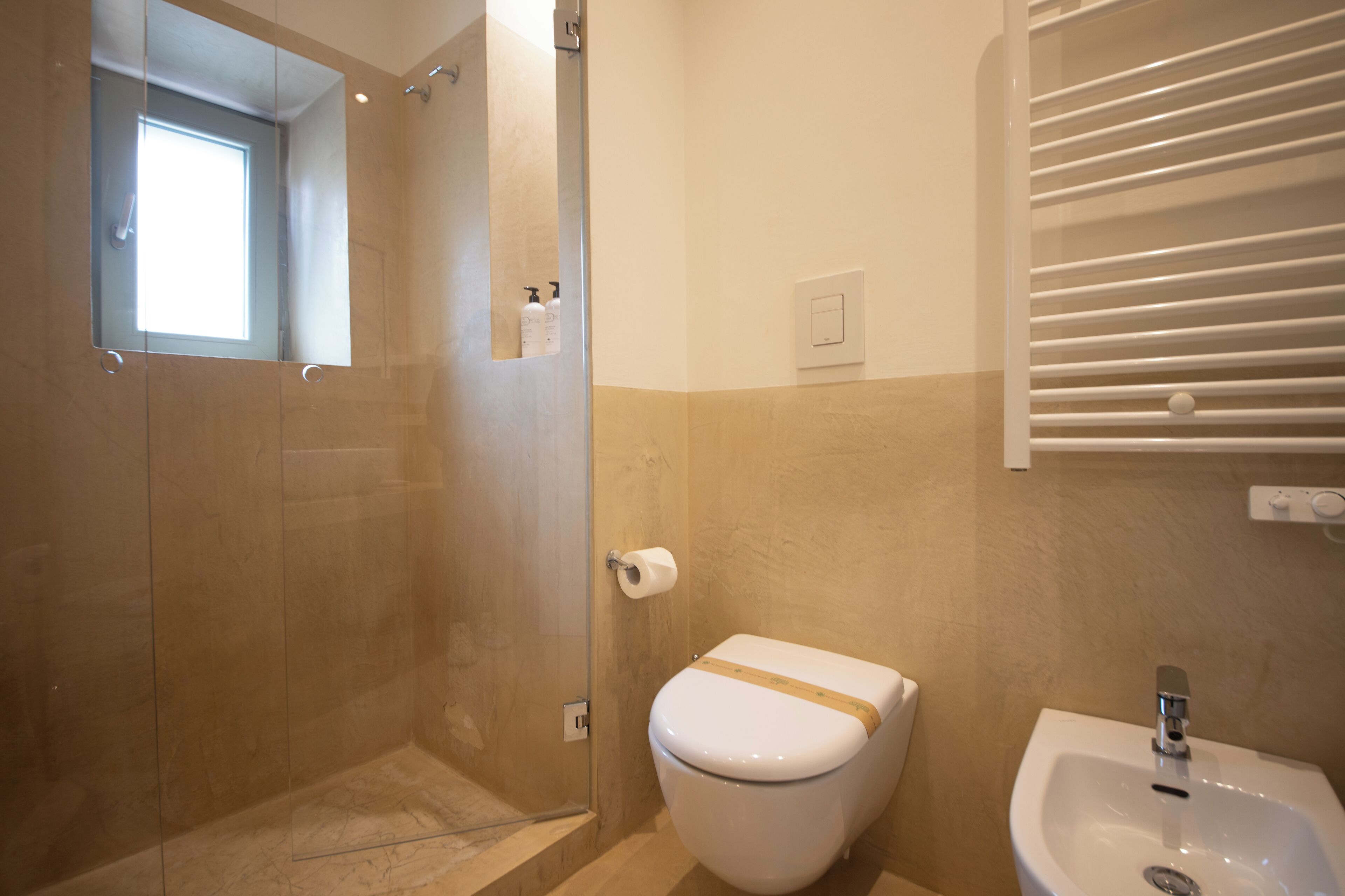 Un baño con cabina de ducha de vidrio, inodoro y lavamanos.