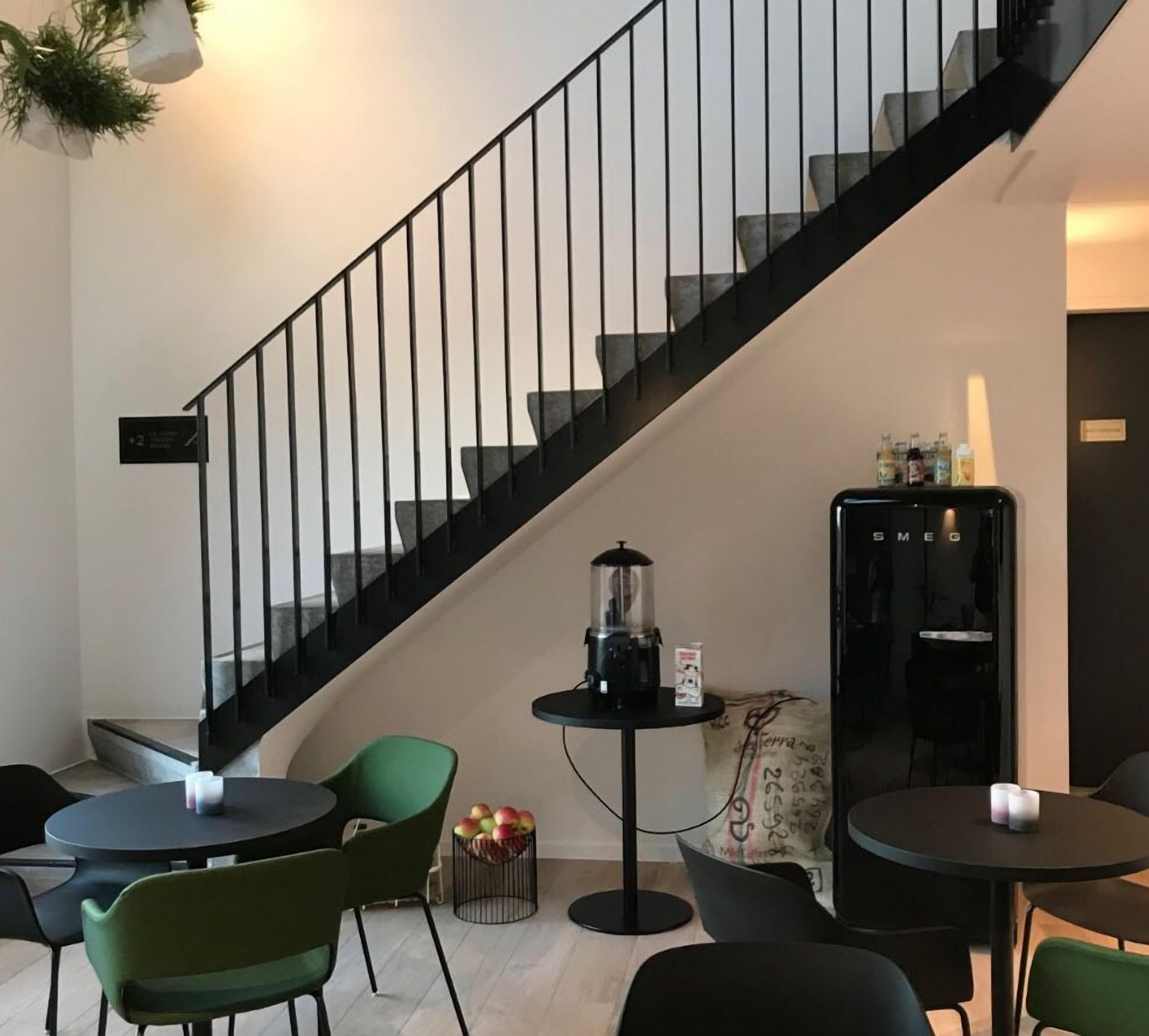 Un interior moderno con una escalera, mesas redondas y sillas.