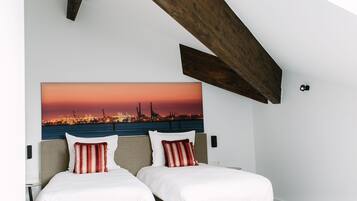 Un dormitorio con dos camas, vistas a la ciudad y vigas de madera a la vista.