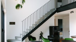 Un interior moderno con una escalera, sillas negras y verdes, y una mesa negra.