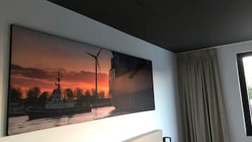 Een groot schilderij van een schip op een rivier bij zonsondergang.