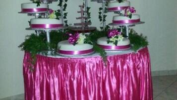 Un pastel de varios niveles, cada uno decorado con flores y cintas, sobre una mesa cubierta con un mantel rosa.