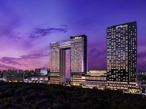 Un hôtel moderne doté d’une architecture remarquable, caractérisée par une structure en arc, de nombreux étages et une enseigne lumineuse.