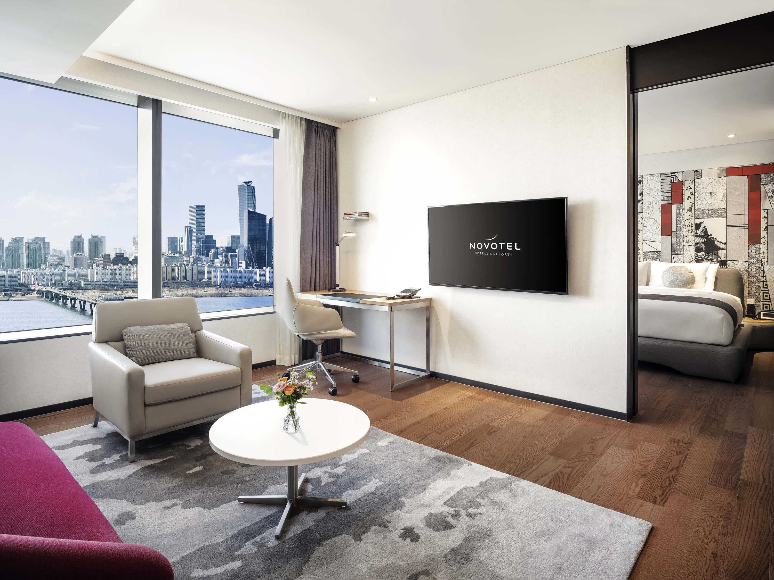 Una habitación de hotel con vista a la ciudad, un escritorio, un televisor y una cama.