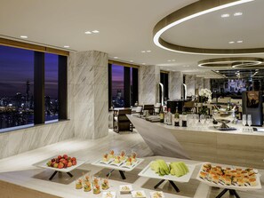 A modern hotel lobby with a city view, marble flooring, and a buffet with various food and drink options. - Novotel Ambassador Seoul Yongsan - Seoul Dragon City (Seoul)