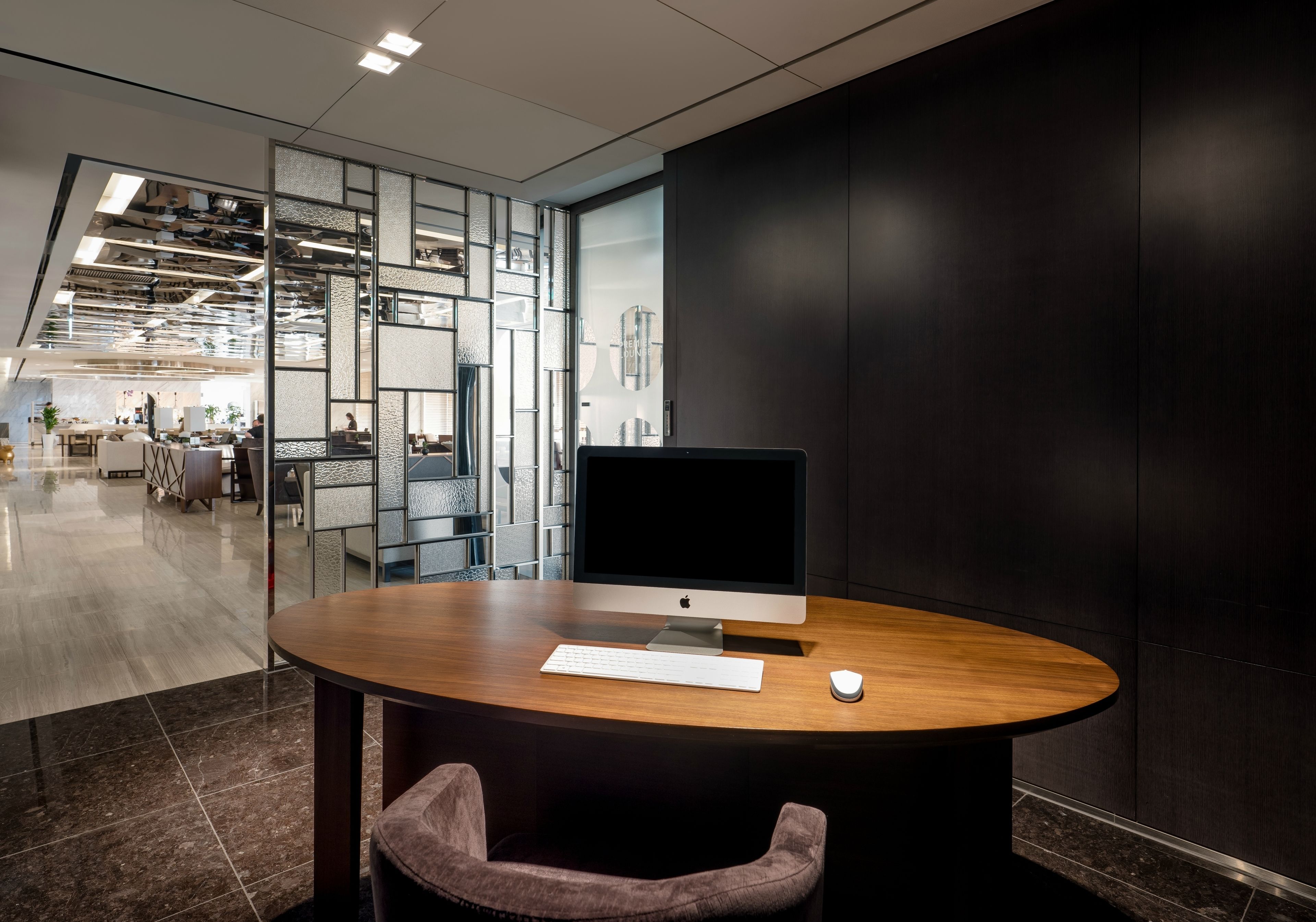 A modern office space with a round wooden table, a large monitor, and a keyboard.
