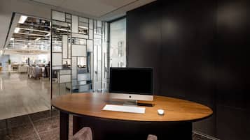Een moderne kantoorruimte met een ronde houten tafel, een groot beeldscherm en een toetsenbord.