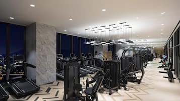 A modern gym with treadmills, elliptical machines, and weight equipment.