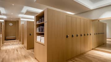 A modern hotel room with wooden flooring, built-in wardrobes, and a bench.