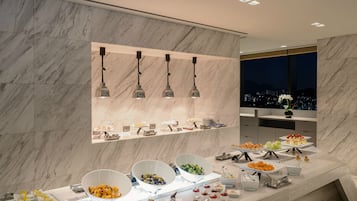 Une chambre d’hôtel moderne avec un mur en marbre, une vue sur la ville et un buffet proposant une variété de plats.