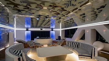A modern lounge area with a central coffee table, striped sofas, and a unique ceiling design.