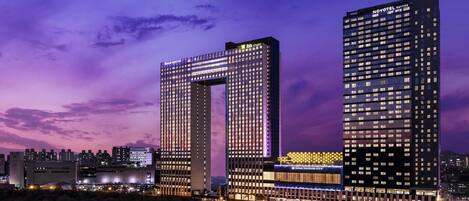 Dos edificios altos con señalización iluminada, uno que dice 'Novotel Suites' y el otro 'Grand Mercure'.