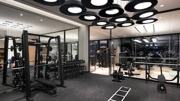 A modern gym with mirrored walls, various exercise equipment, and a black and white color scheme.