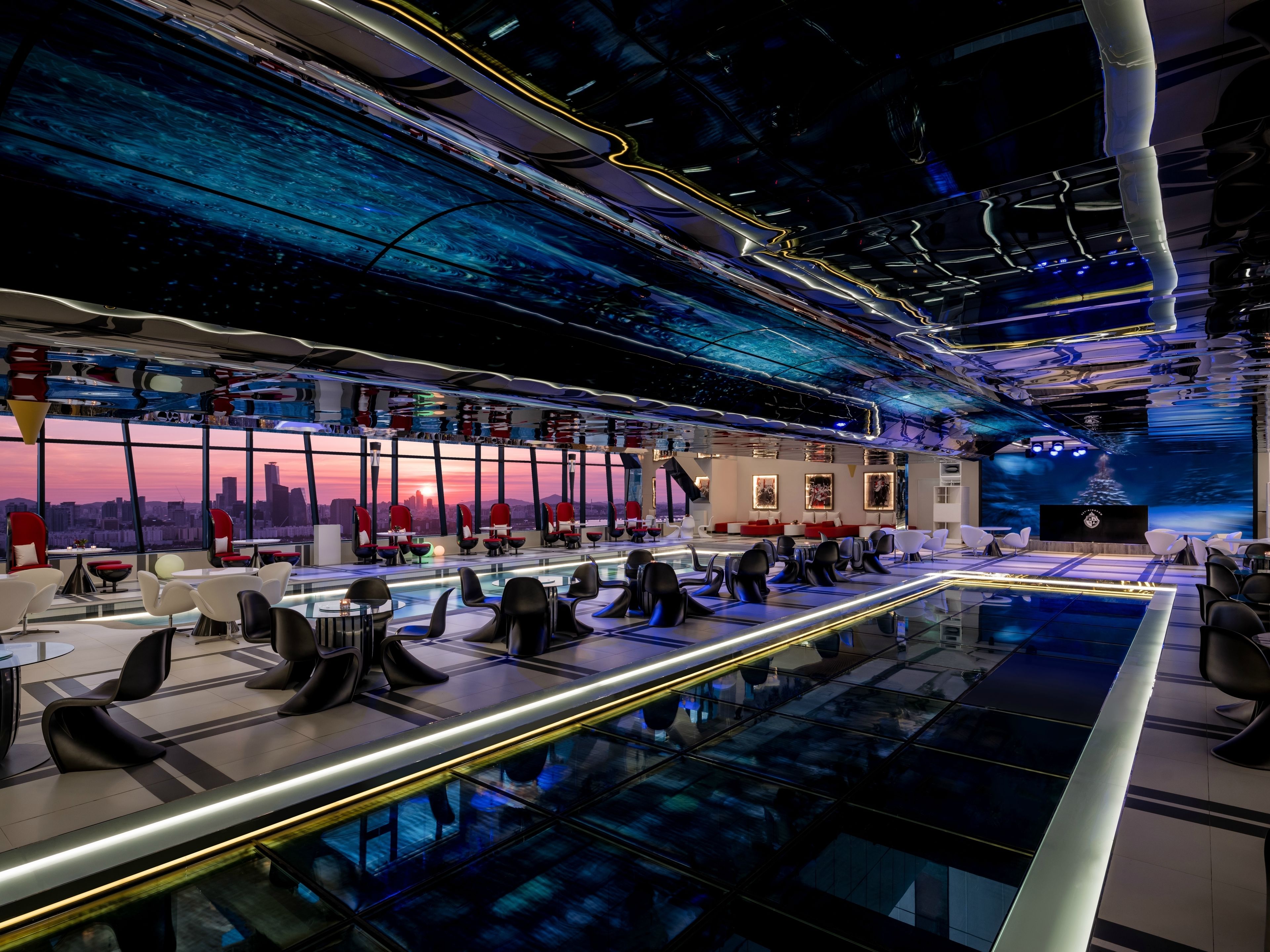 A modern conference room with a city view, glass tables, and red chairs.