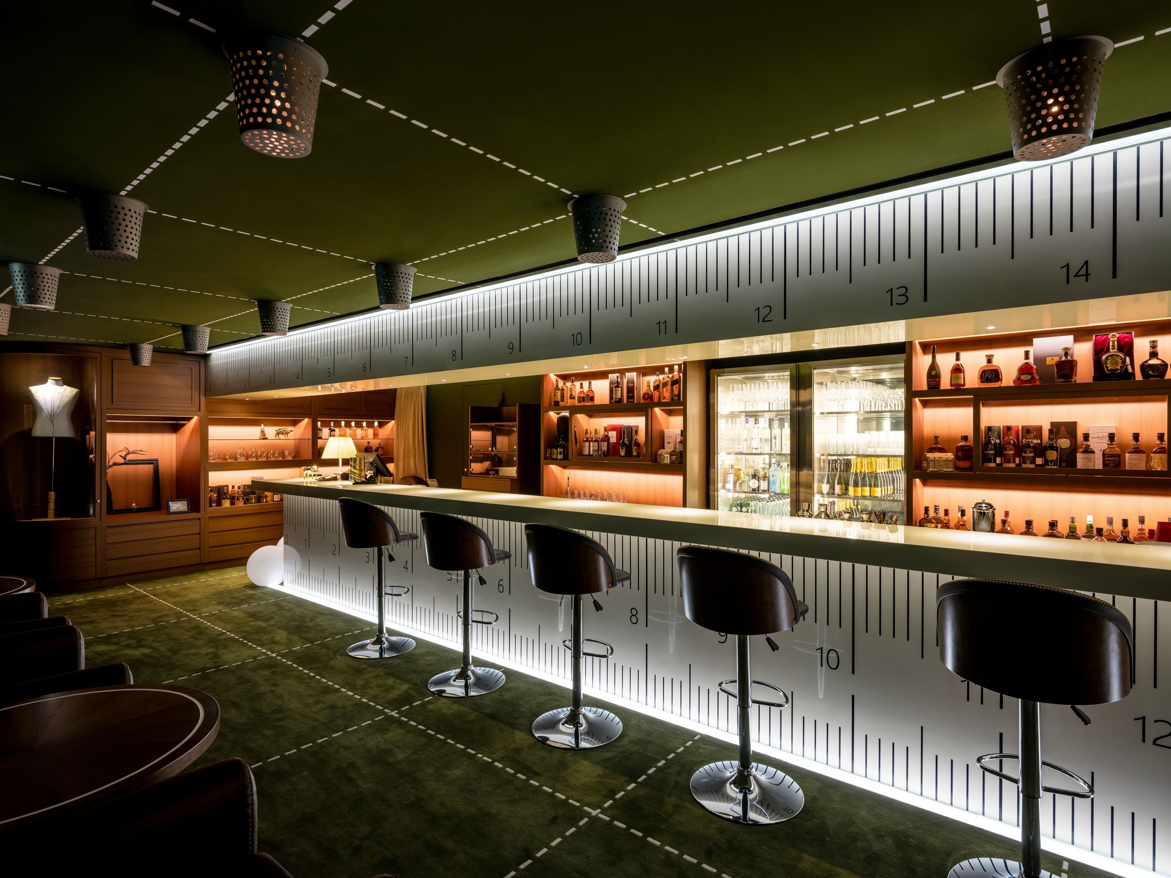 A bar area with a counter, stools, and shelves of bottles.