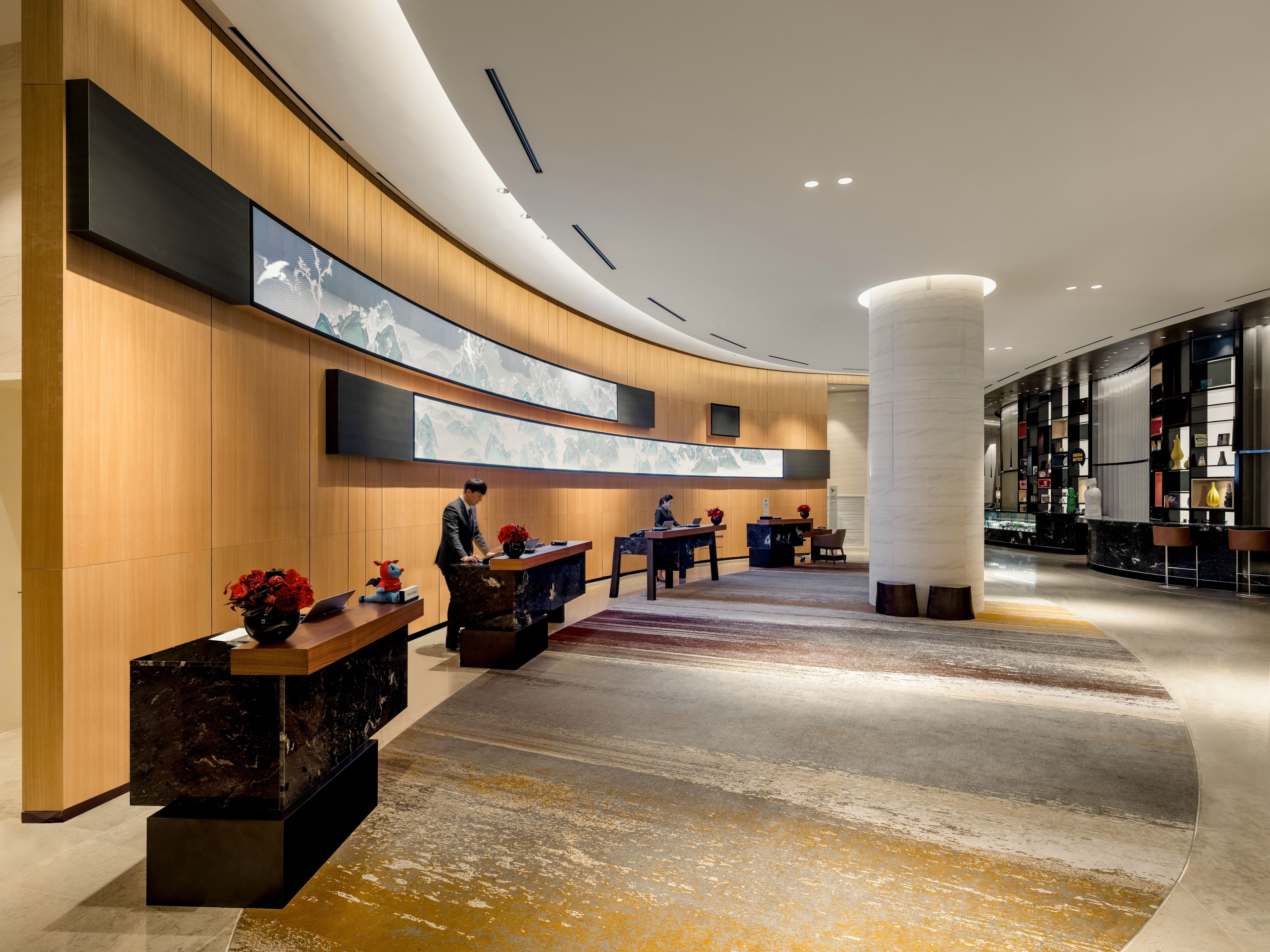 A modern hotel lobby with a curved reception desk, a large digital art display, and a marble floor.