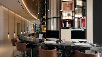 A modern bar area with marble countertops, leather bar stools, and multiple Apple iMac computers.