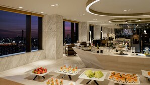 A modern hotel lobby with a city view, marble flooring, and a buffet with various food items. - Novotel Suites Ambassador Seoul Yongsan - Seoul Dragon City (Seoul)