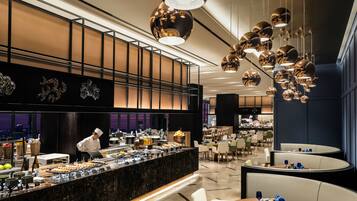 A modern hotel lobby with a marble reception desk, seating areas, and a view of the cityscape.