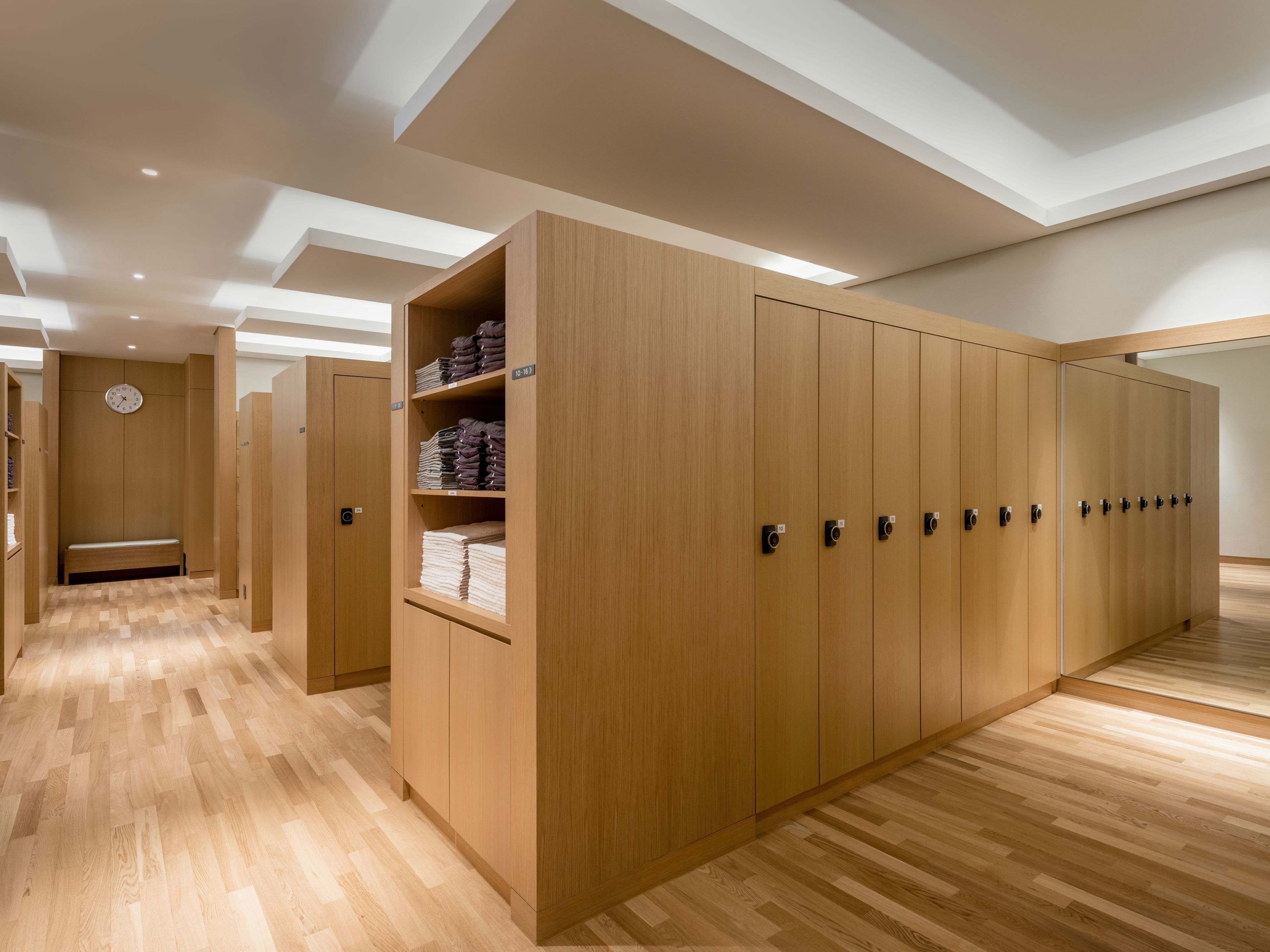 Une chambre d’hôtel moderne avec un plancher en bois, des placards intégrés et un banc.