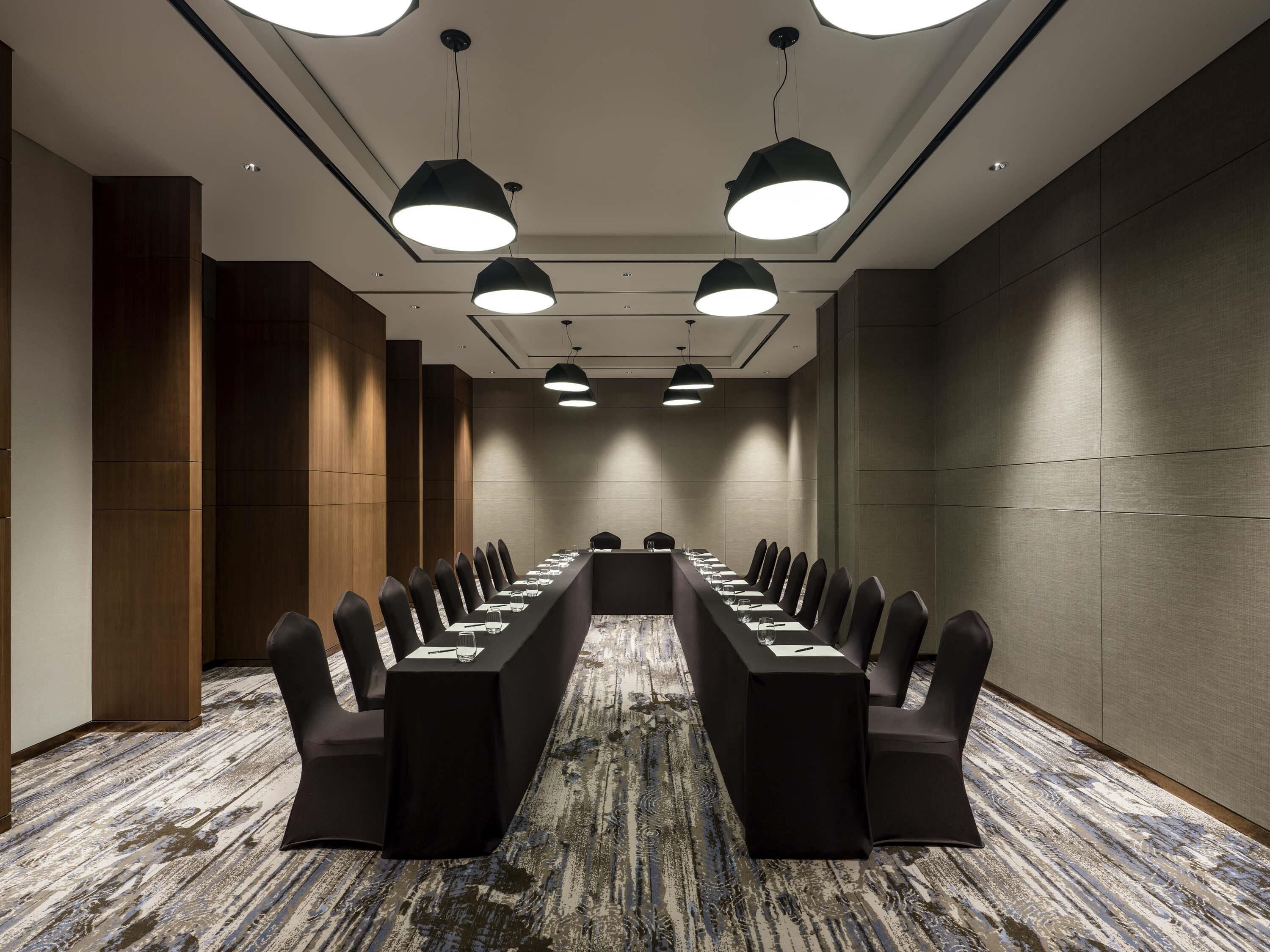 A conference room with a long table, chairs, and pendant lighting.