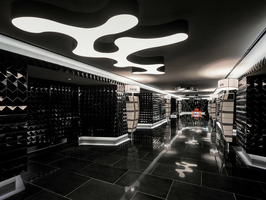 A modern, sleek hotel corridor with black tiled floors and geometric wall designs.