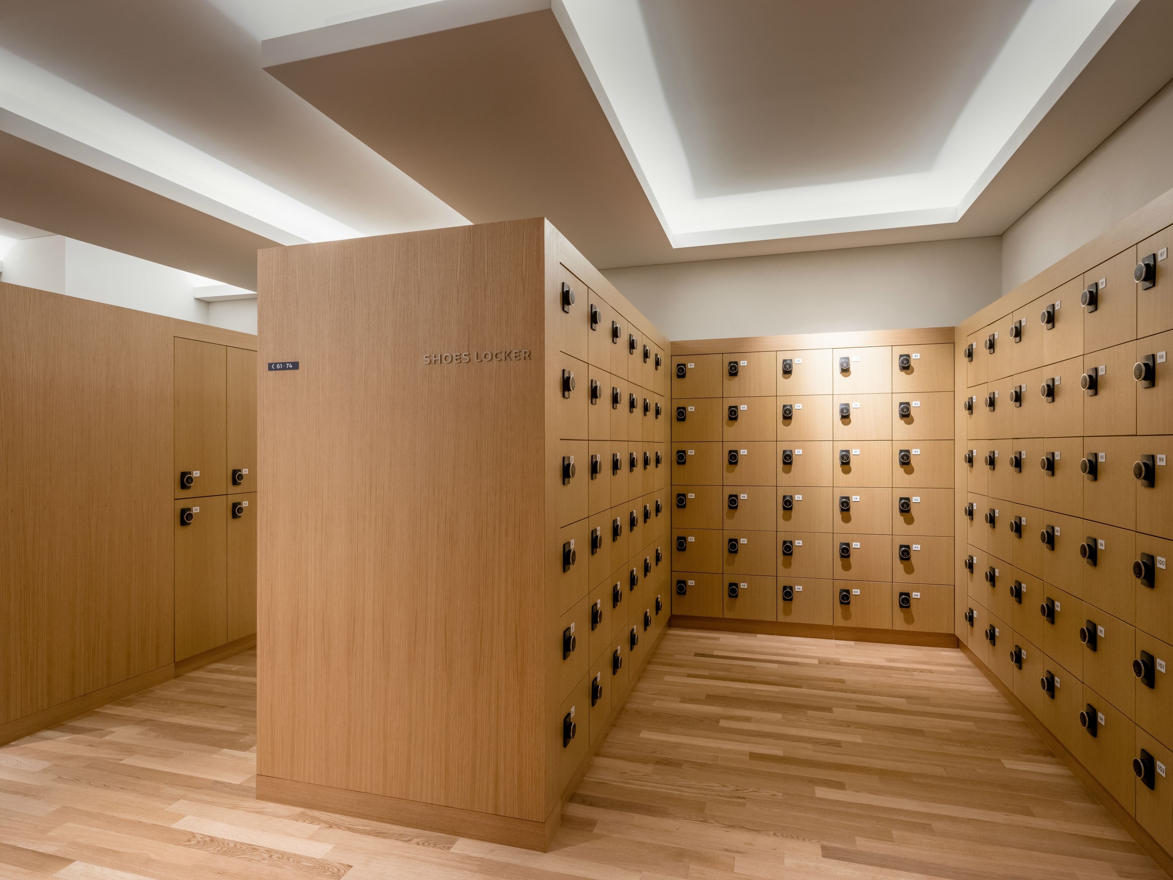 A modern locker room with multiple wooden lockers and a central shoe locker.