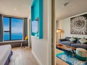 A hotel room with a large window, a sofa, a small table, and a decorative wall piece. - ibis Styles Nha Trang (Nha Trang)