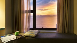 A room with a bed, a window with curtains, a green mug, and a pillow on the windowsill. - ibis Styles Nha Trang (Nha Trang)