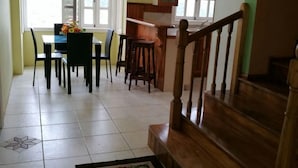 Een eetgedeelte met een tafel en stoelen, een keuken met houten kastjes en een trap.