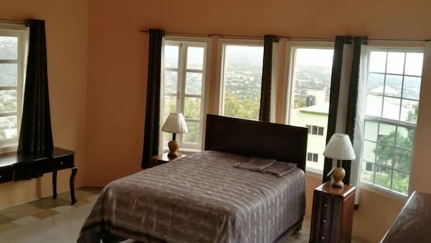 Een slaapkamer met een groot bed, twee ramen en een houten plafond.