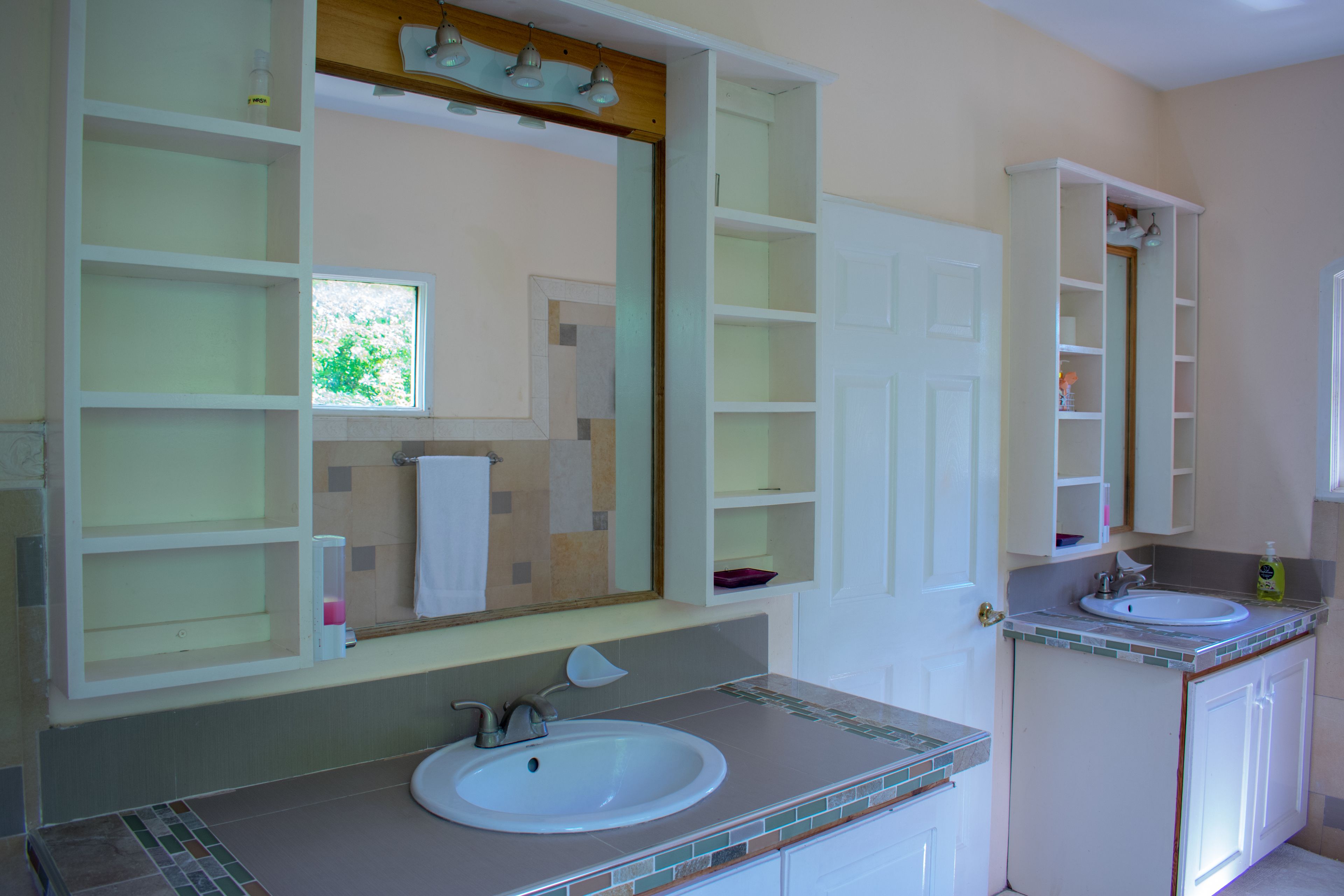A bathroom with a white sink, a large mirror, and a window.