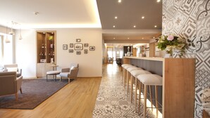 A modern hotel lobby with a bar area, seating, and a patterned floor.