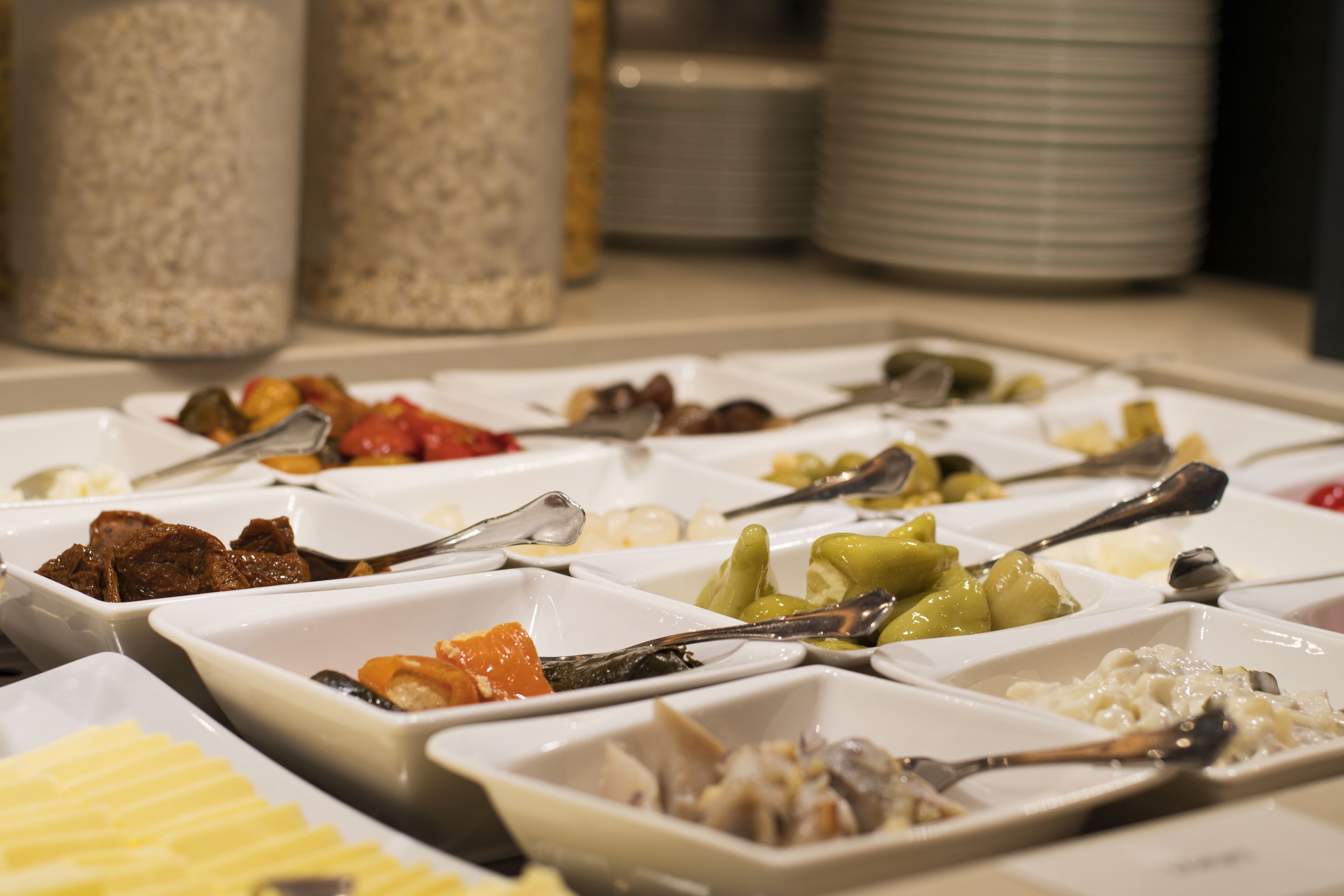 A buffet with various food items in white square dishes, arranged on a table.