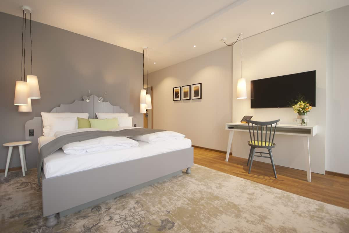 A modern bedroom with a bed, bedside tables, a desk, and a chair.