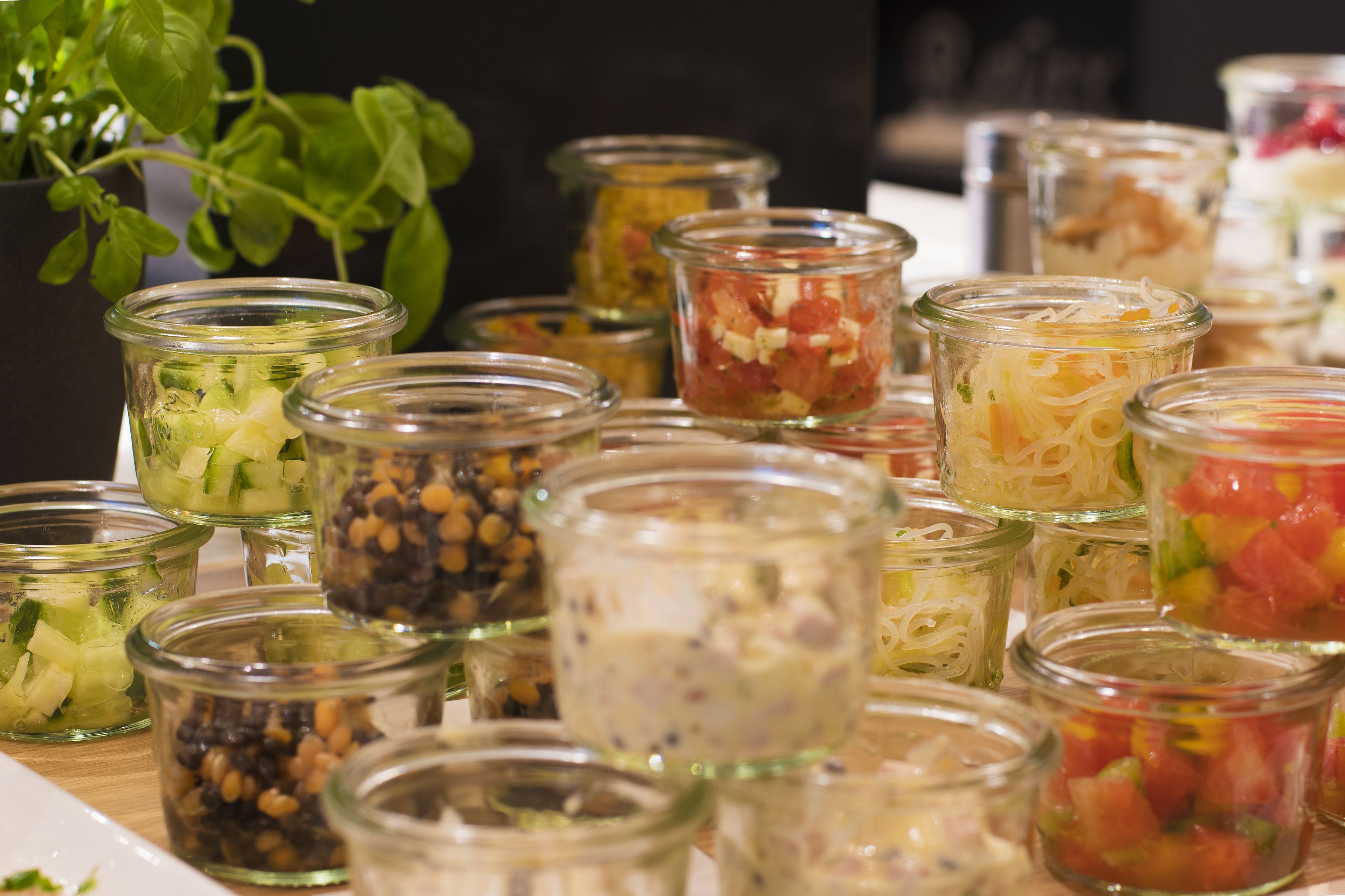 Verschillende soorten eten in kleine glazen potjes, waaronder ingelegde groenten en salades.