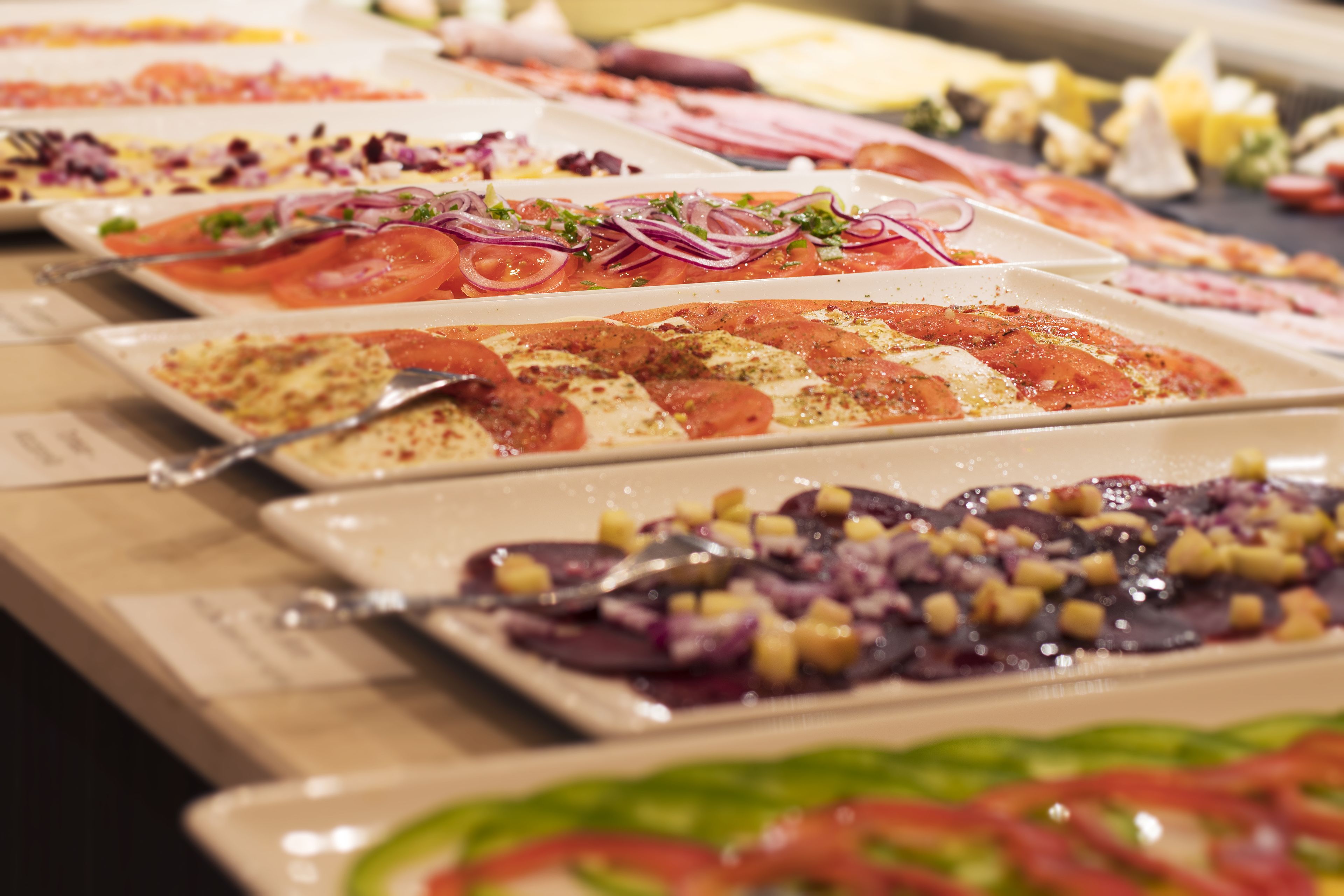 A buffet with various dishes including salads, pasta, and meats.