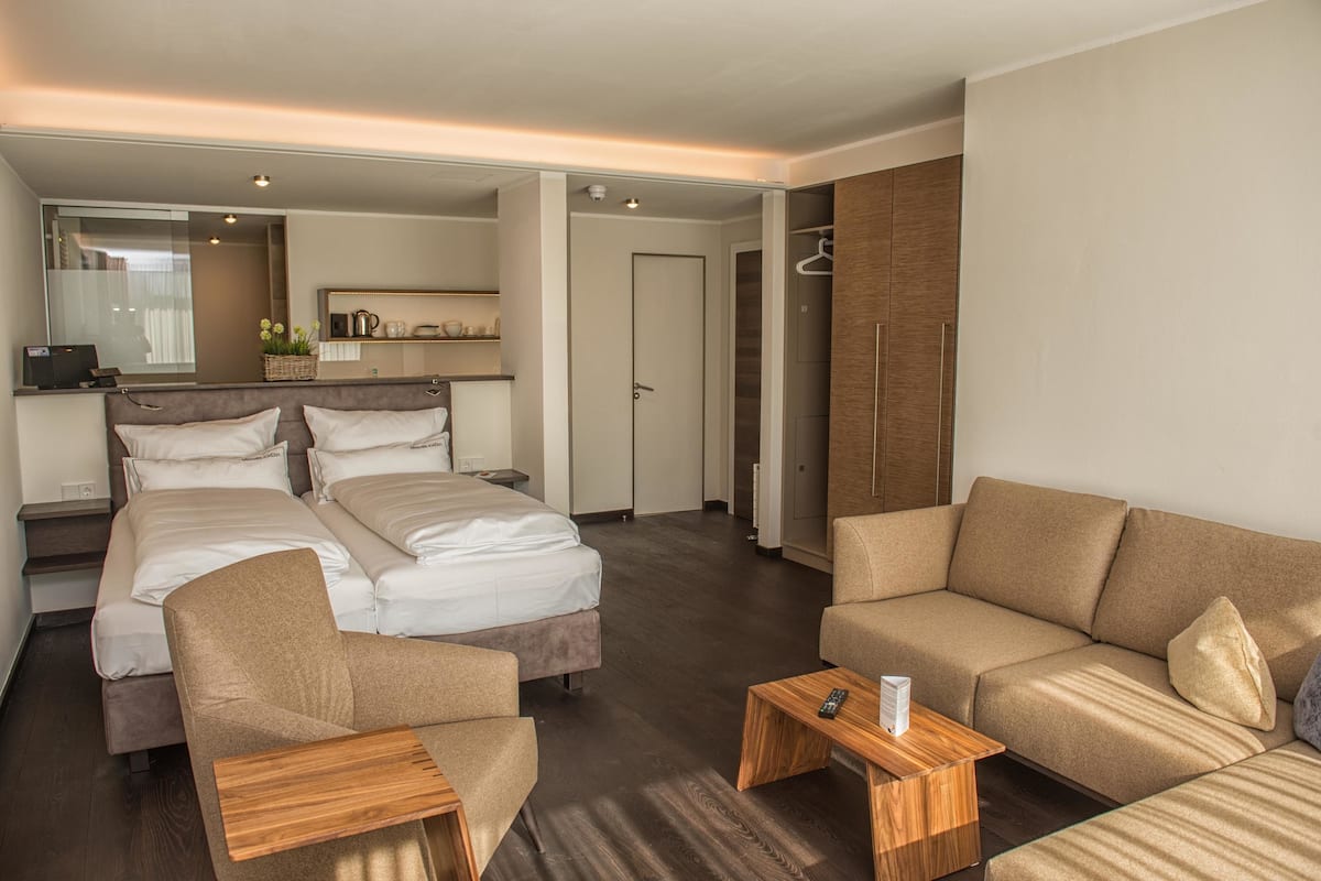 Habitación de hotel con dos camas, un sofá, una mesa de centro, un espejo y un armario.