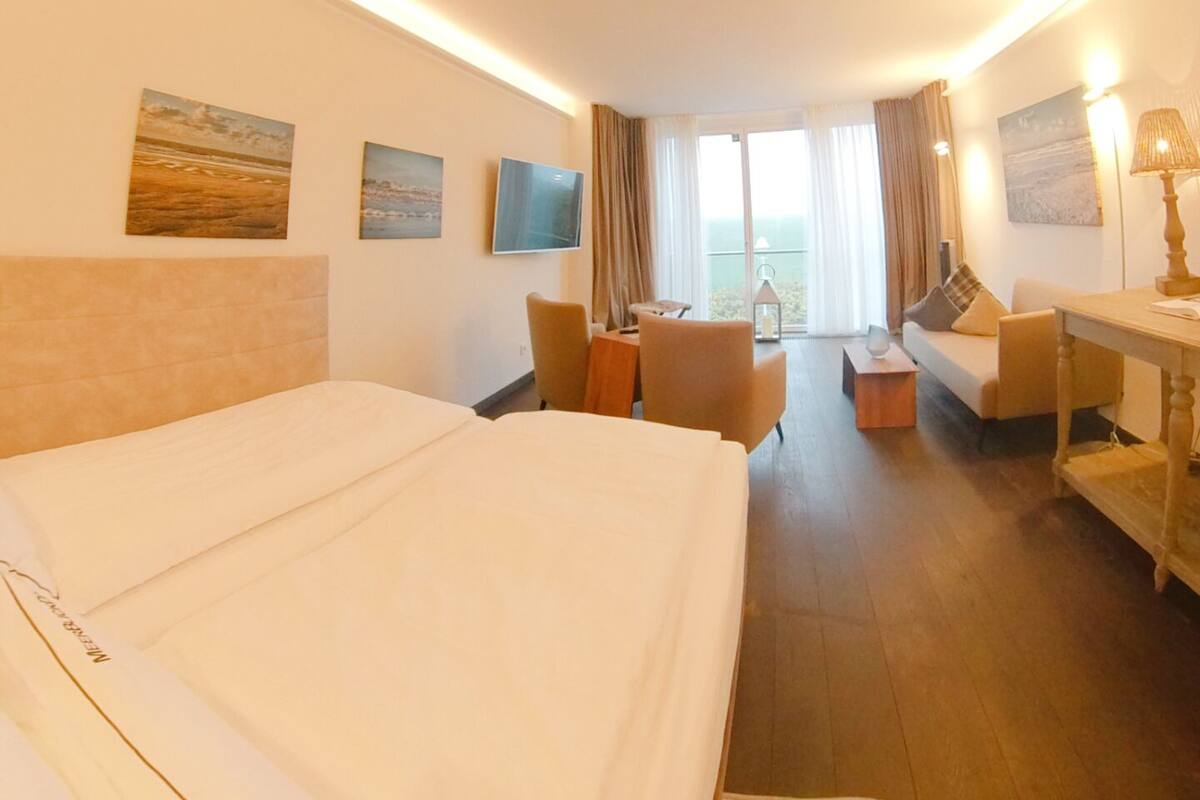 Una habitación de hotel con una cama grande, un escritorio, un sofá y vistas al mar.