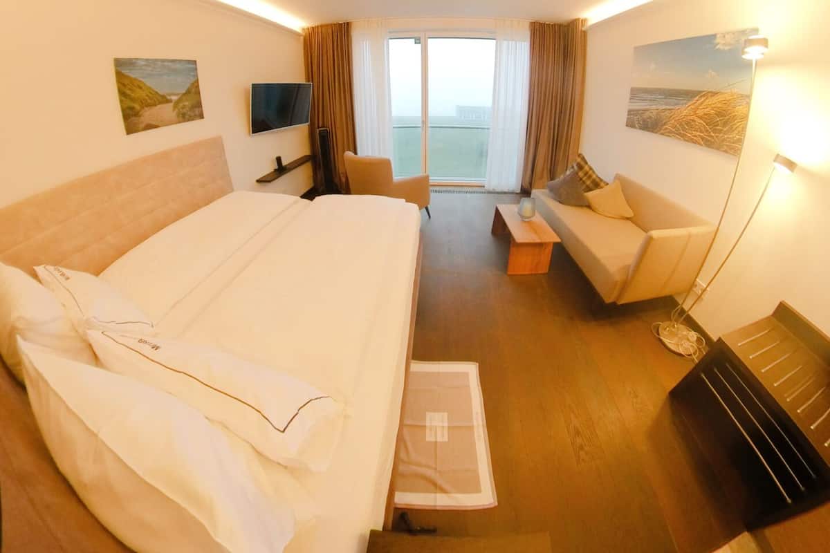 Habitación de hotel con una cama grande, un sofá, un televisor y vistas al exterior.
