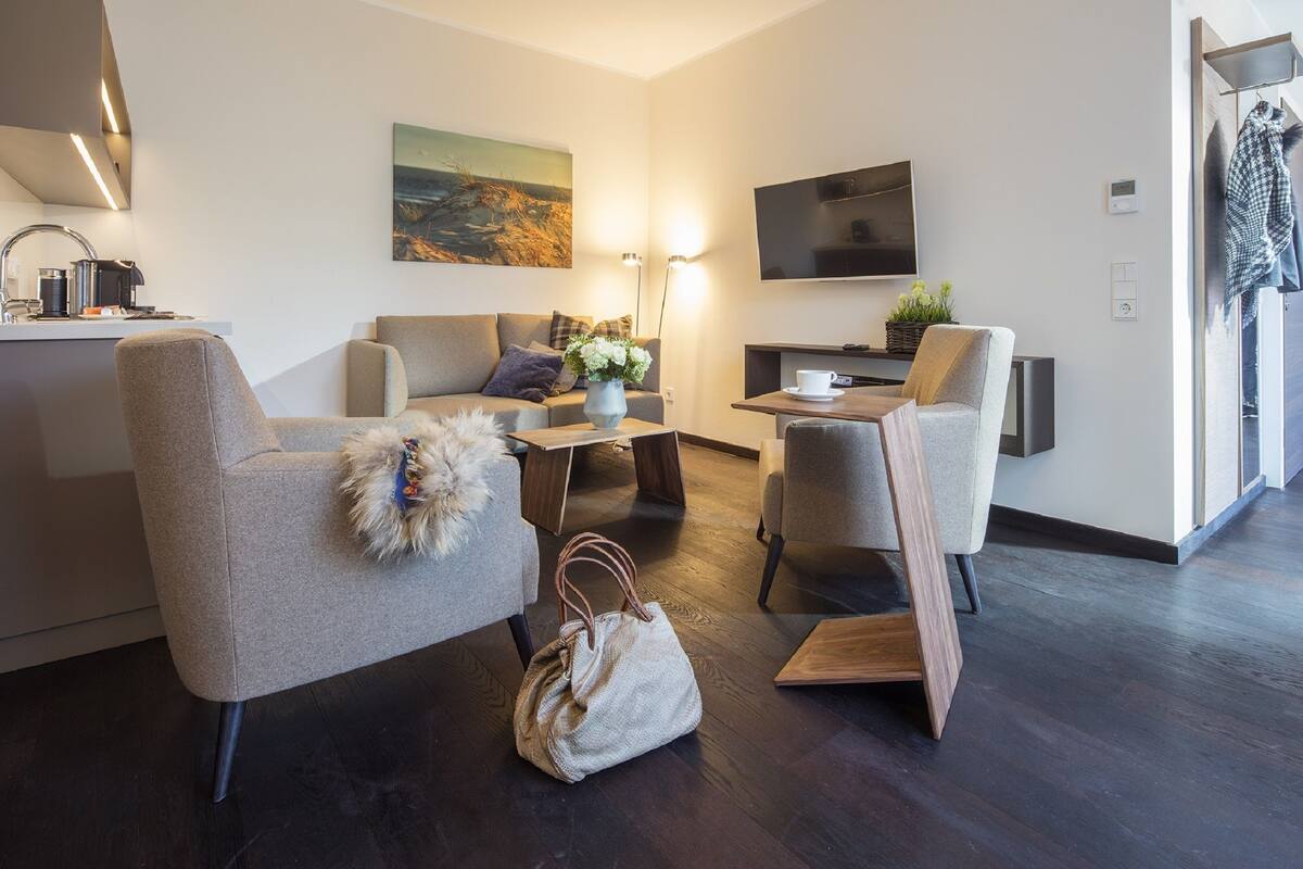 Una sala de estar moderna con un sofá, sillones, una mesa de centro y un televisor.