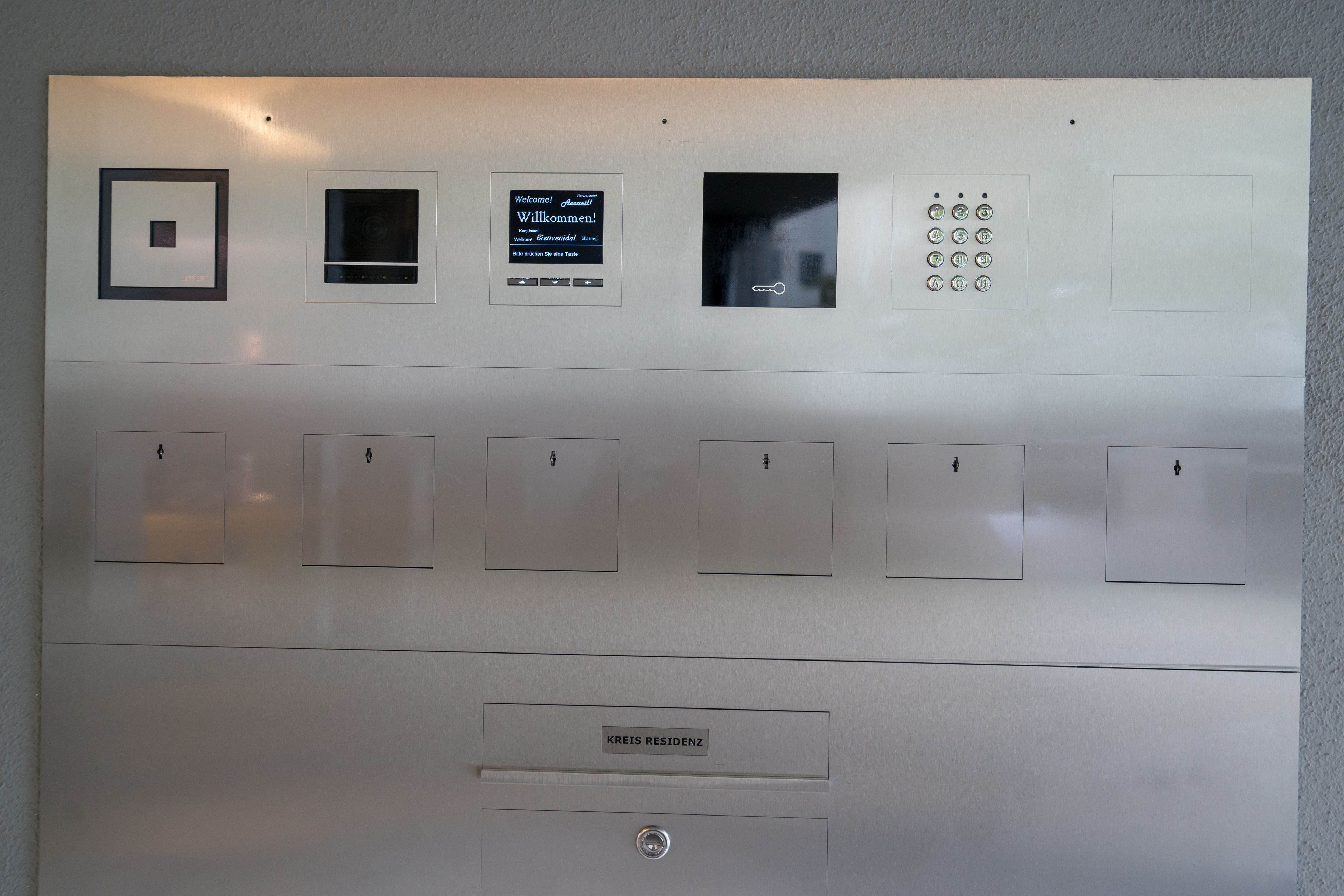 A control panel with a welcome message, a security camera, and numbered buttons for an elevator.