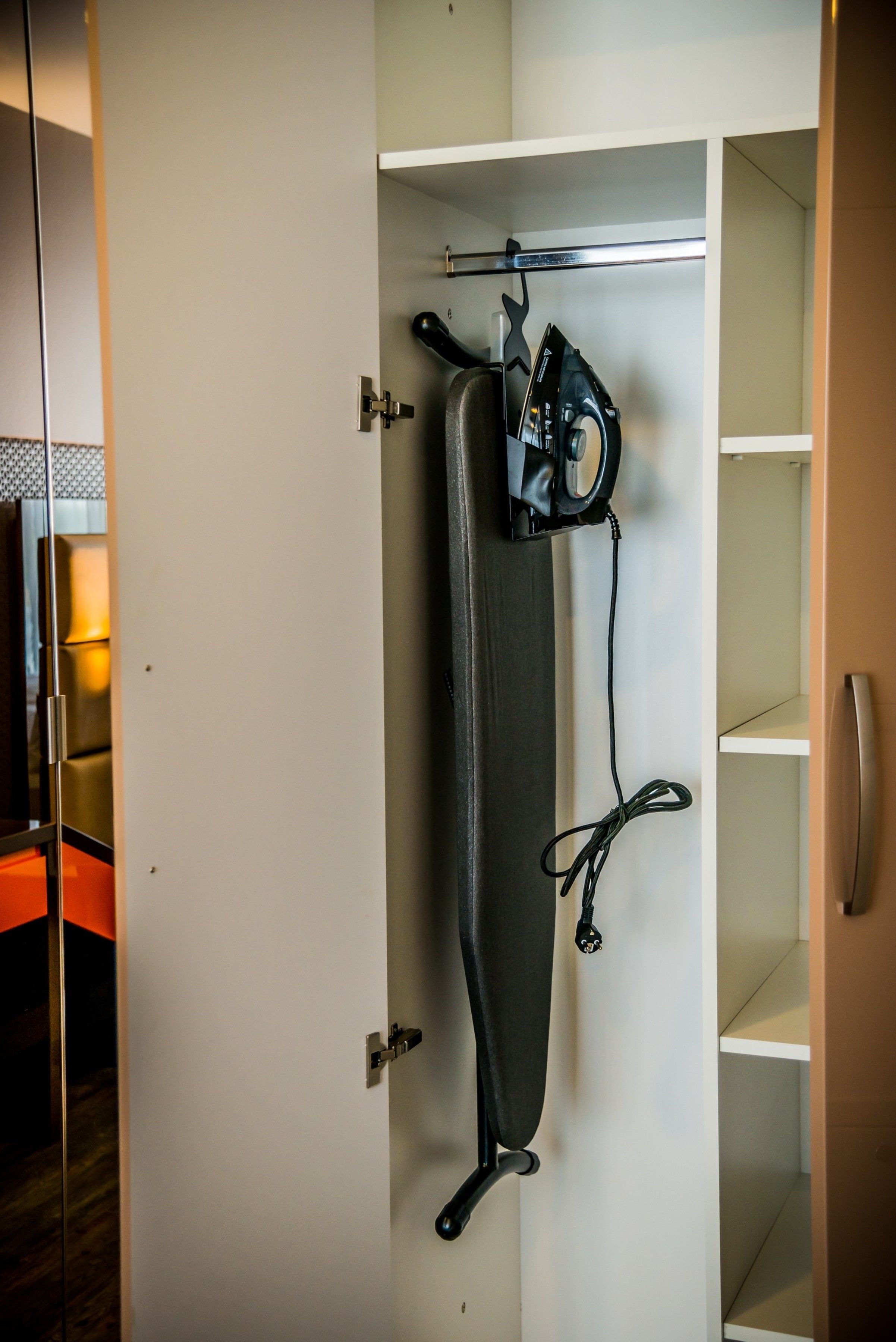 Ein Schrank mit Kleiderstange, Staubsauger und Mehrfachsteckdose.