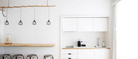 Una cocina moderna con armarios blancos, una encimera de madera y una lámpara colgante.