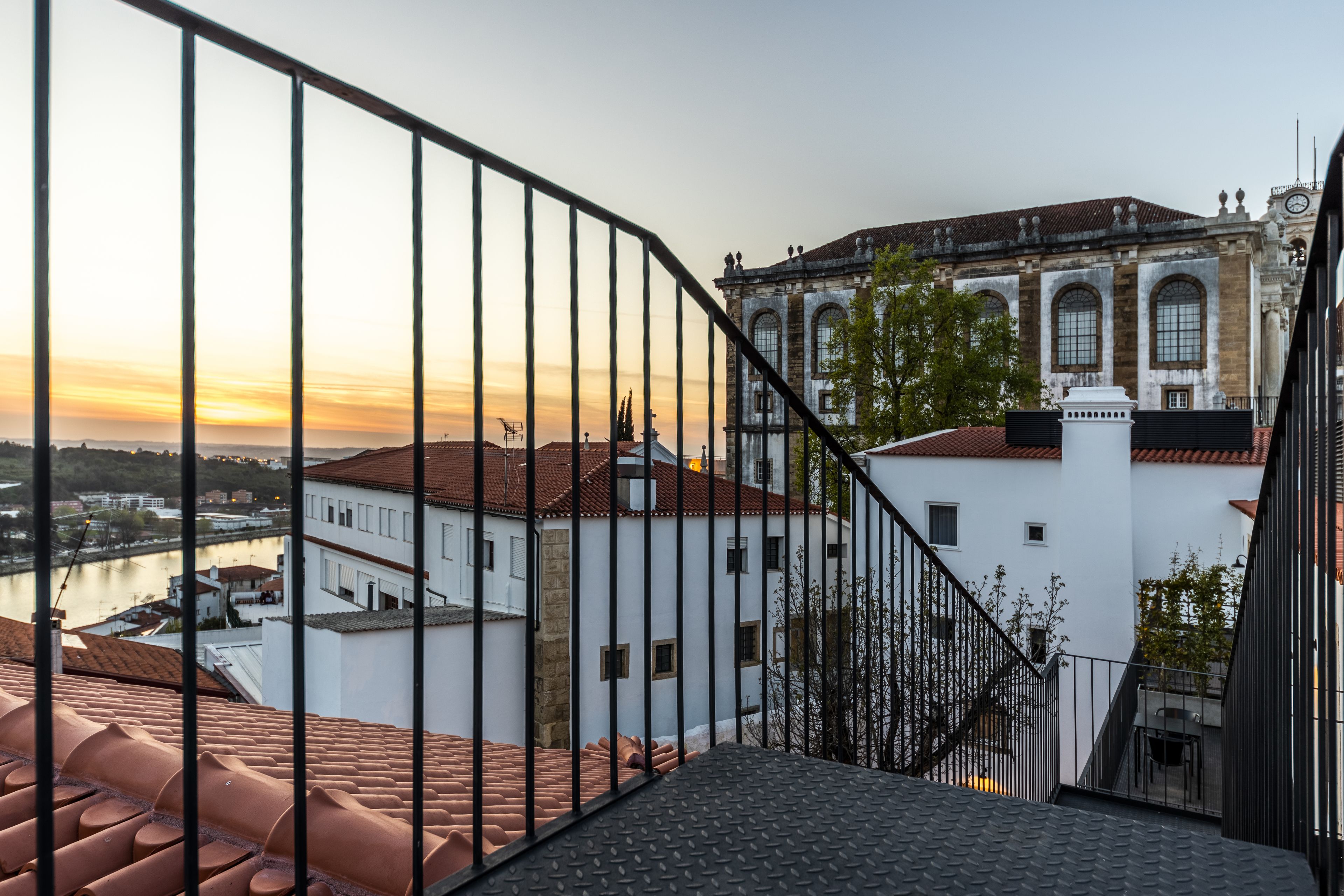 A staircase leading to a terrace with a view of a historic building and a river.