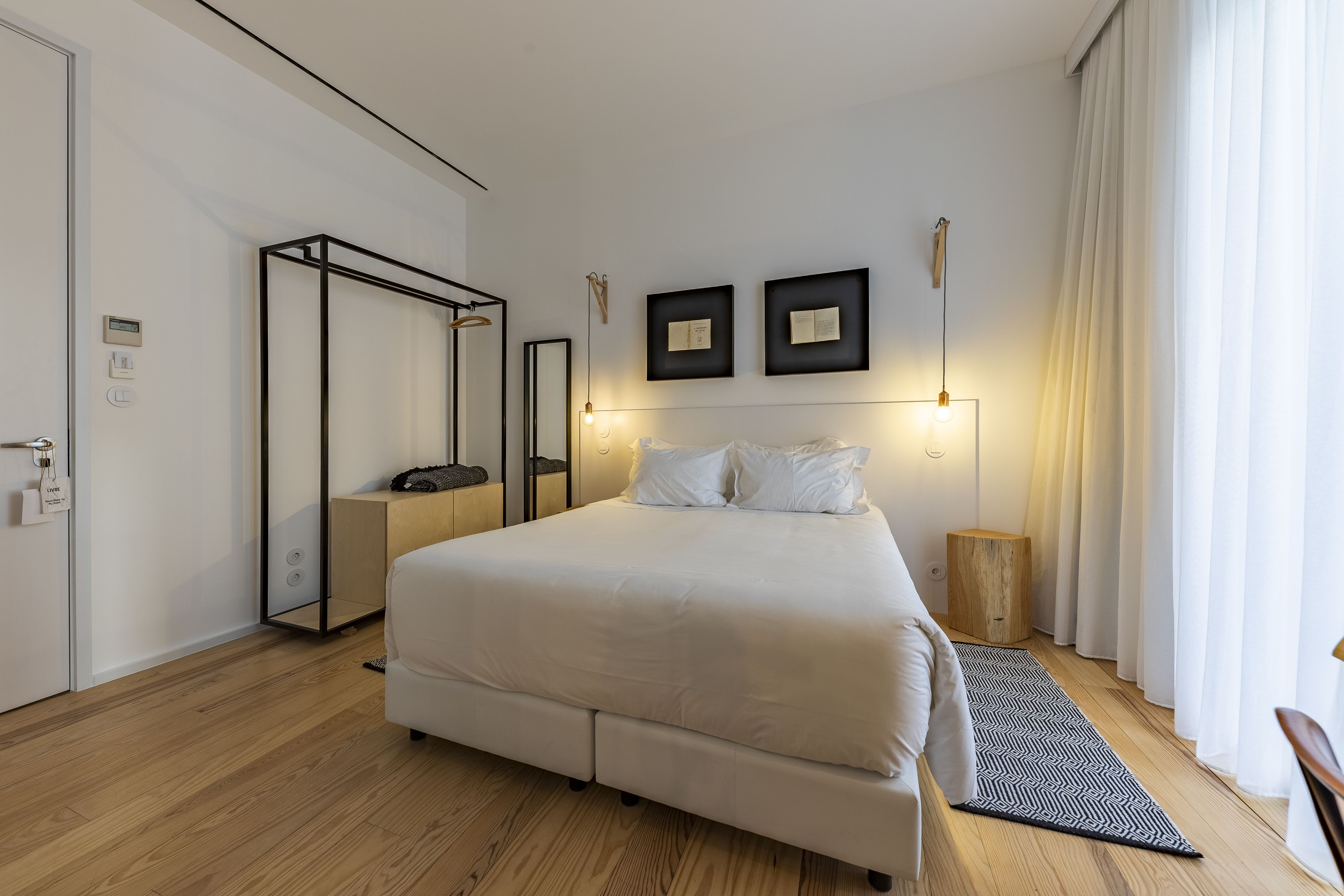 Un dormitorio moderno con una cama grande, suelo de madera, un espejo y una mesita de noche.