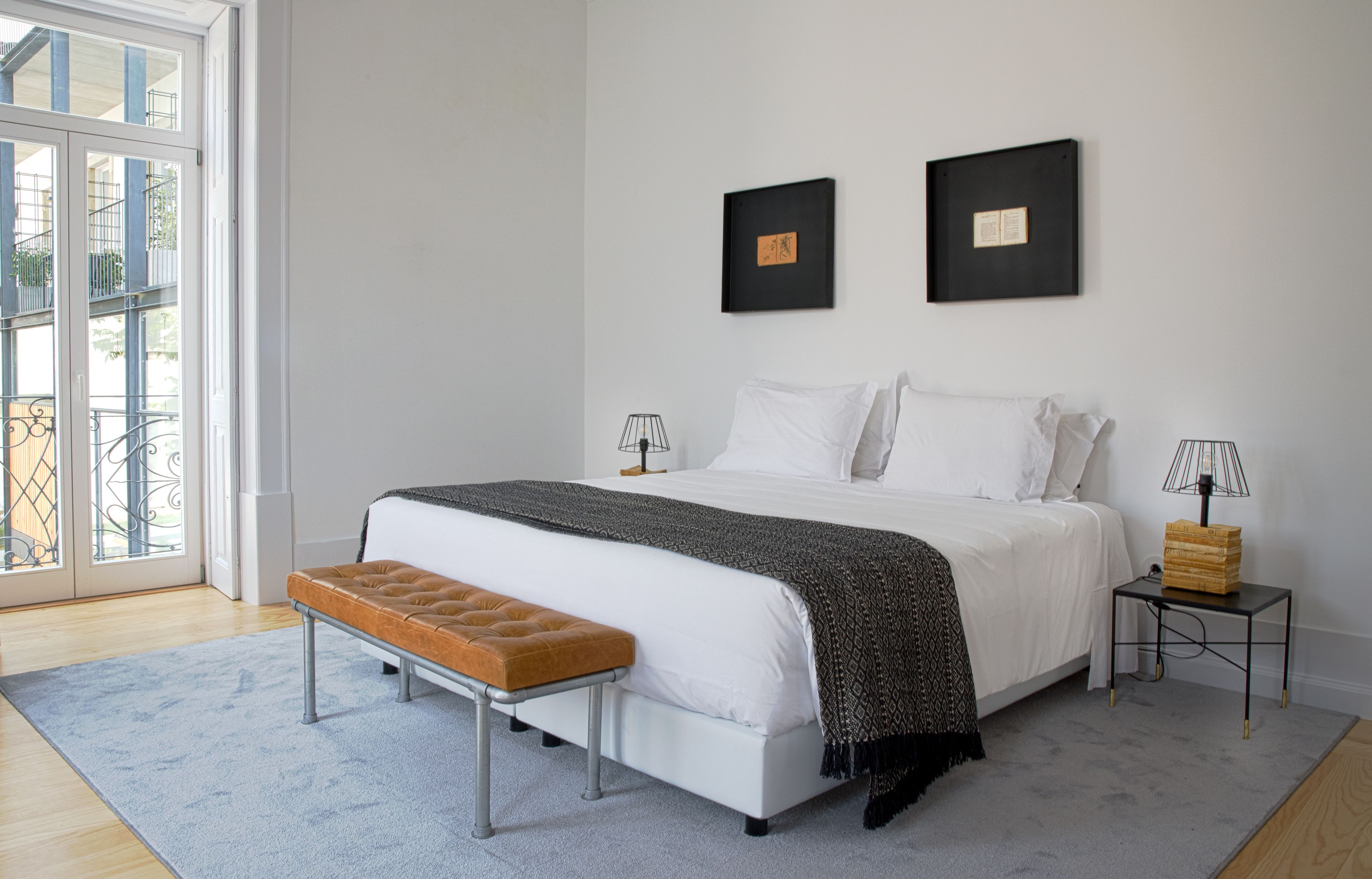 A bedroom with a bed, a bench, a bedside table, and two framed pictures on the wall.