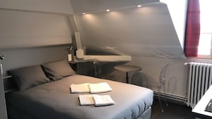 A modern bedroom with a large bed, a small desk, and a window with curtains. - Smartappart Troyes (Troyes)